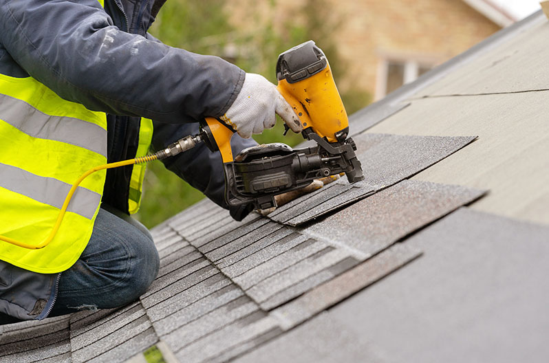 Roofer installing new roofing shingles on a single-family home
