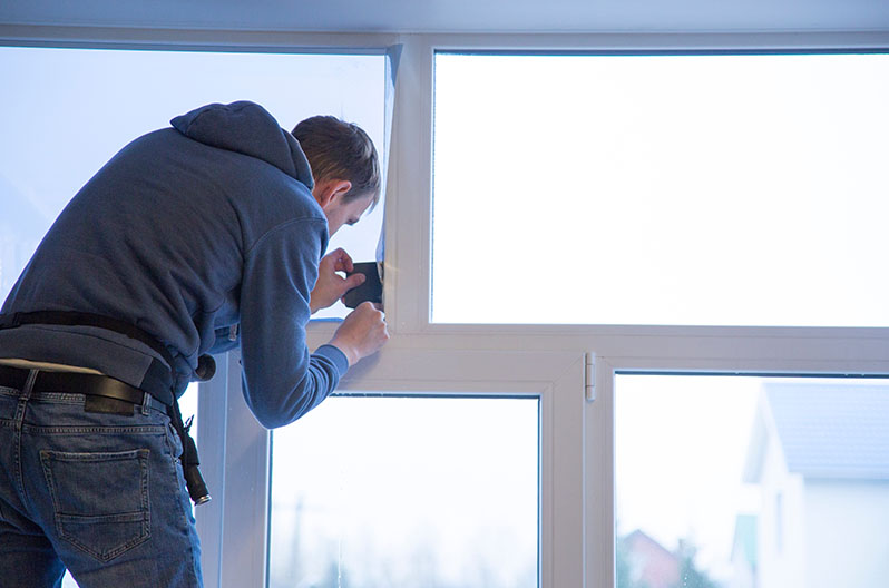 A contractor installing window tint in a home